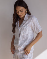 Woman wearing comfortable 100% bamboo PJ set showing a short sleeve pyjama top with button up design, pocket and bold geometric print in light grey and white.