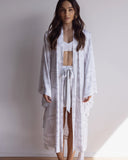 Woman wearing a comfortable kimono-style robe. Made from silky-soft, breathable bamboo. Featuring a unique print design and a tie waist for an adjustable fit and hidden pockets. Perfect for relaxing.