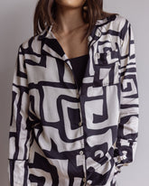 Woman wearing comfortable, breathable 100% bamboo PJ set showing a long sleeve pyjama top with button up design, pocket and bold geometric print in black and cream.