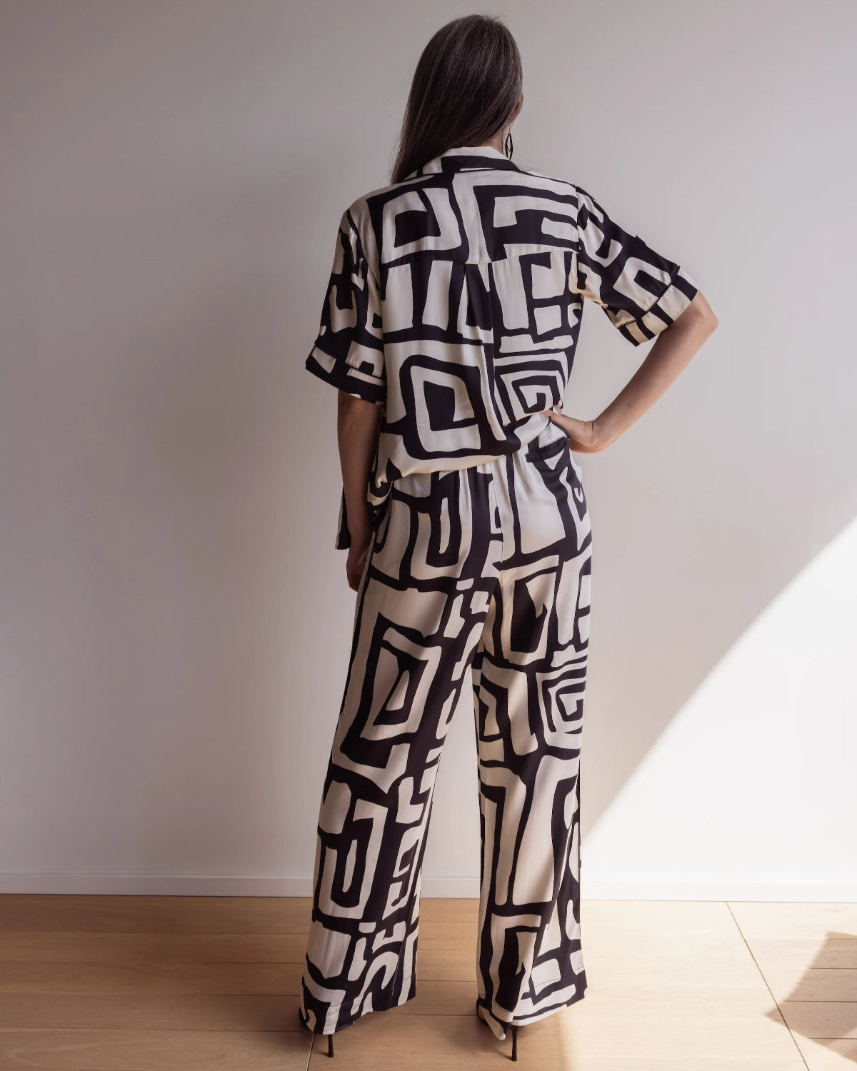 Back of a woman wearing bamboo pyjamas with a short sleeve shirt and pants. Bold geometric print in black and cream colours.