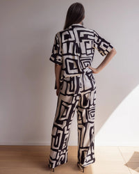 Back of a woman wearing bamboo pyjamas with a short sleeve shirt and pants. Bold geometric print in black and cream colours.