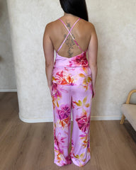 Woman wearing a pink floral pyjama set. The back shows cami top with crossed, adjustable spaghetti straps and matching pants.