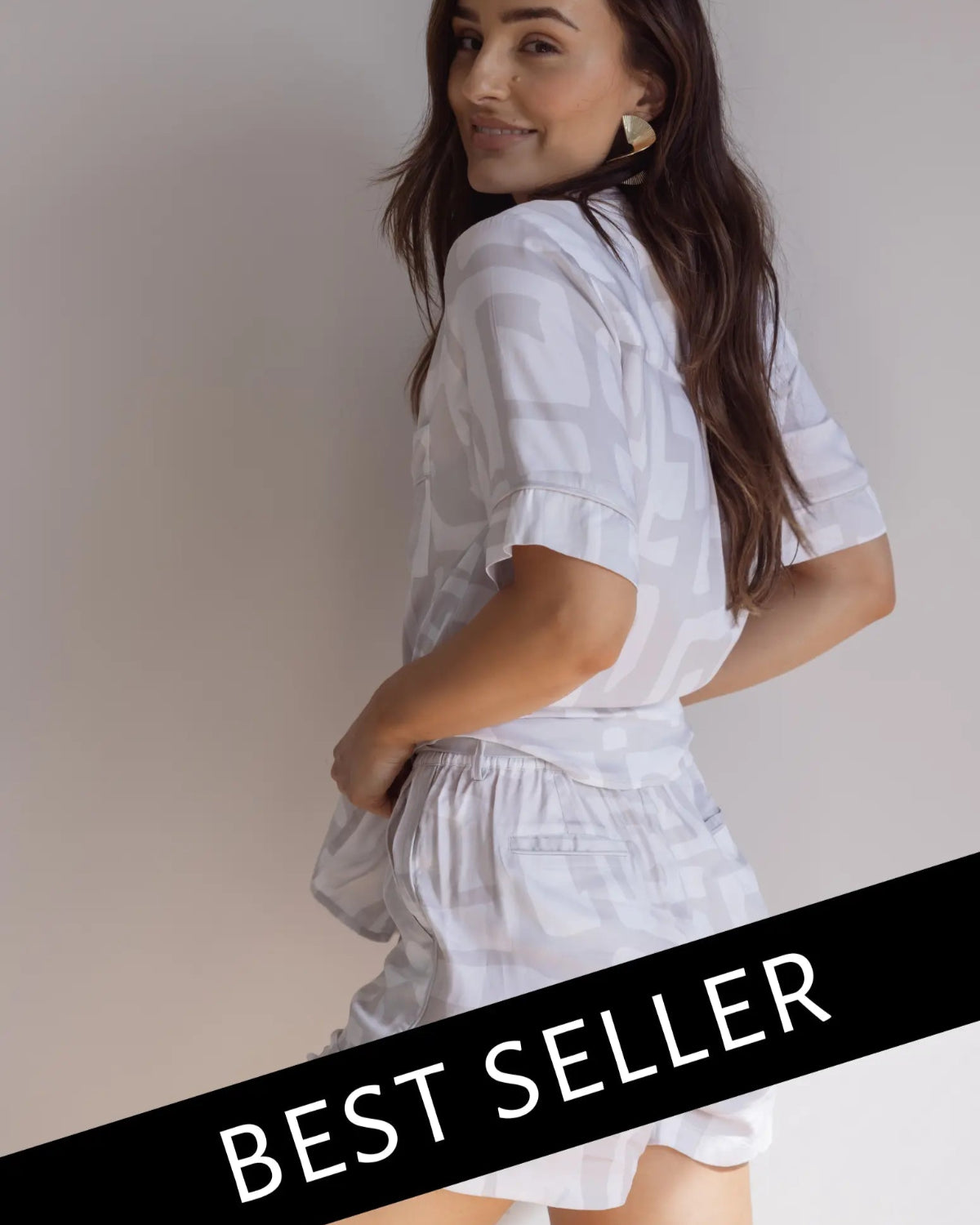 A female model wearing a short sleeve button-down bamboo pyjama top and matching PJ shorts with a graphic pattern, in a standing pose with a 'BEST SELLER' text overlay.
