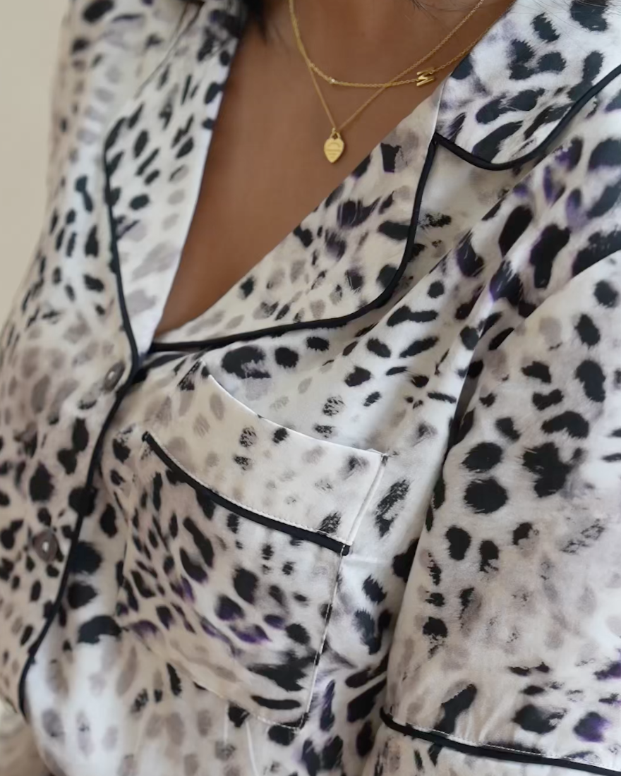 Close up of a pyjama top made from silky soft bamboo viscose satin in a muted leopard print. With dark piping, shell buttons and front pocket.