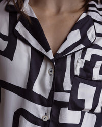 close up detail of a bamboo black and white pyjama top showing a collar with black piping, shell buttons and a pocket on the left side