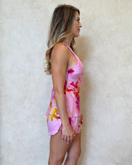 Woman wearing a pink floral pyjama set with cami top and shorts.