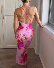 Back of a woman wearing a pink floral slip dress with cross over spaghetti straps and a low back.