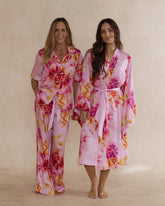 Two women in pink floral bamboo sleepwear. One in a kimono style robe, the other in a pyjama set with short sleeves and pants. These products are sold as a sleepwear bundle for extra savings.
