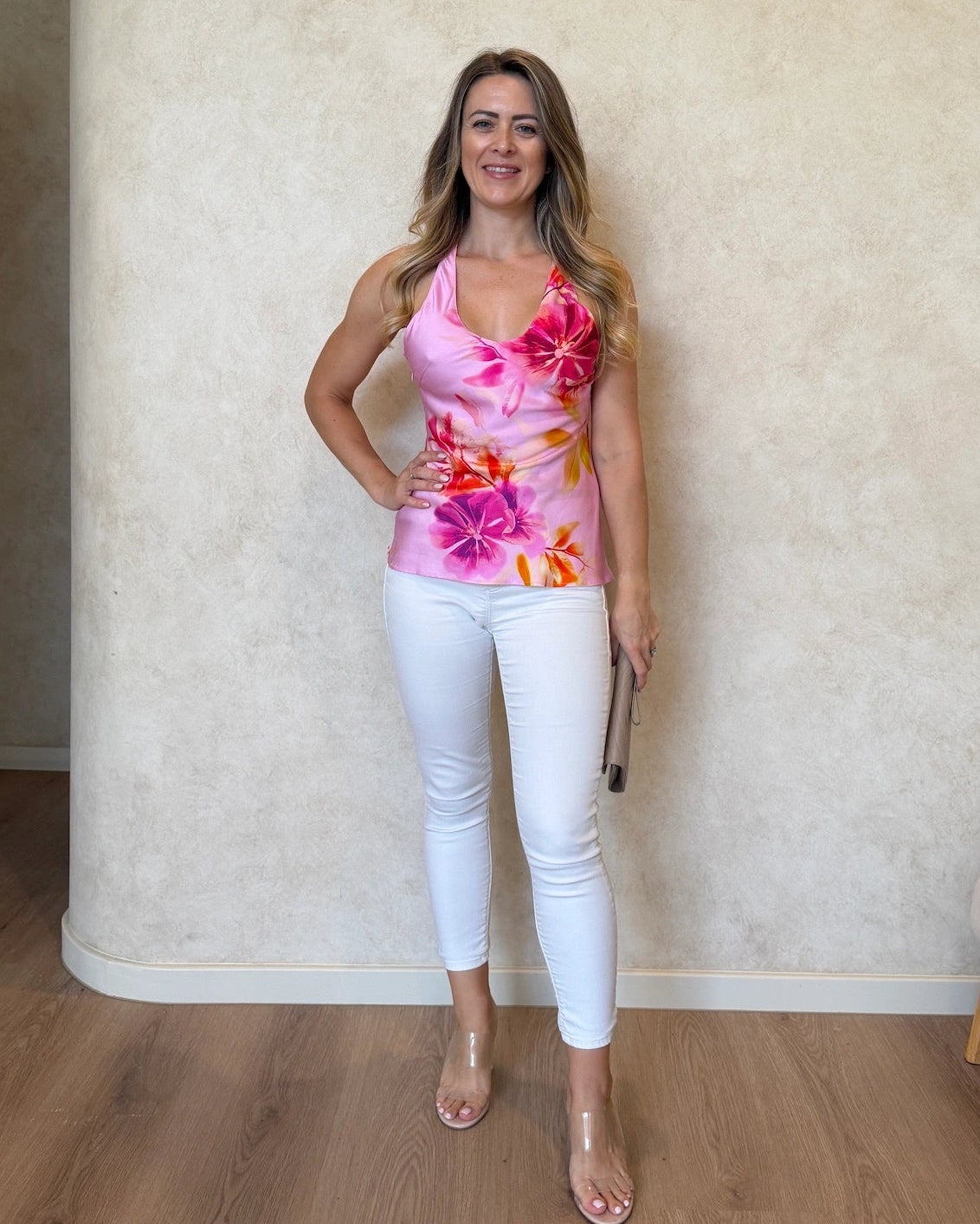 Woman wearing a floral cami top with v-neckline and white pants