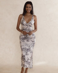 Woman wearing a silky soft leopard print slip dress with low neckline, side split and fitted style.