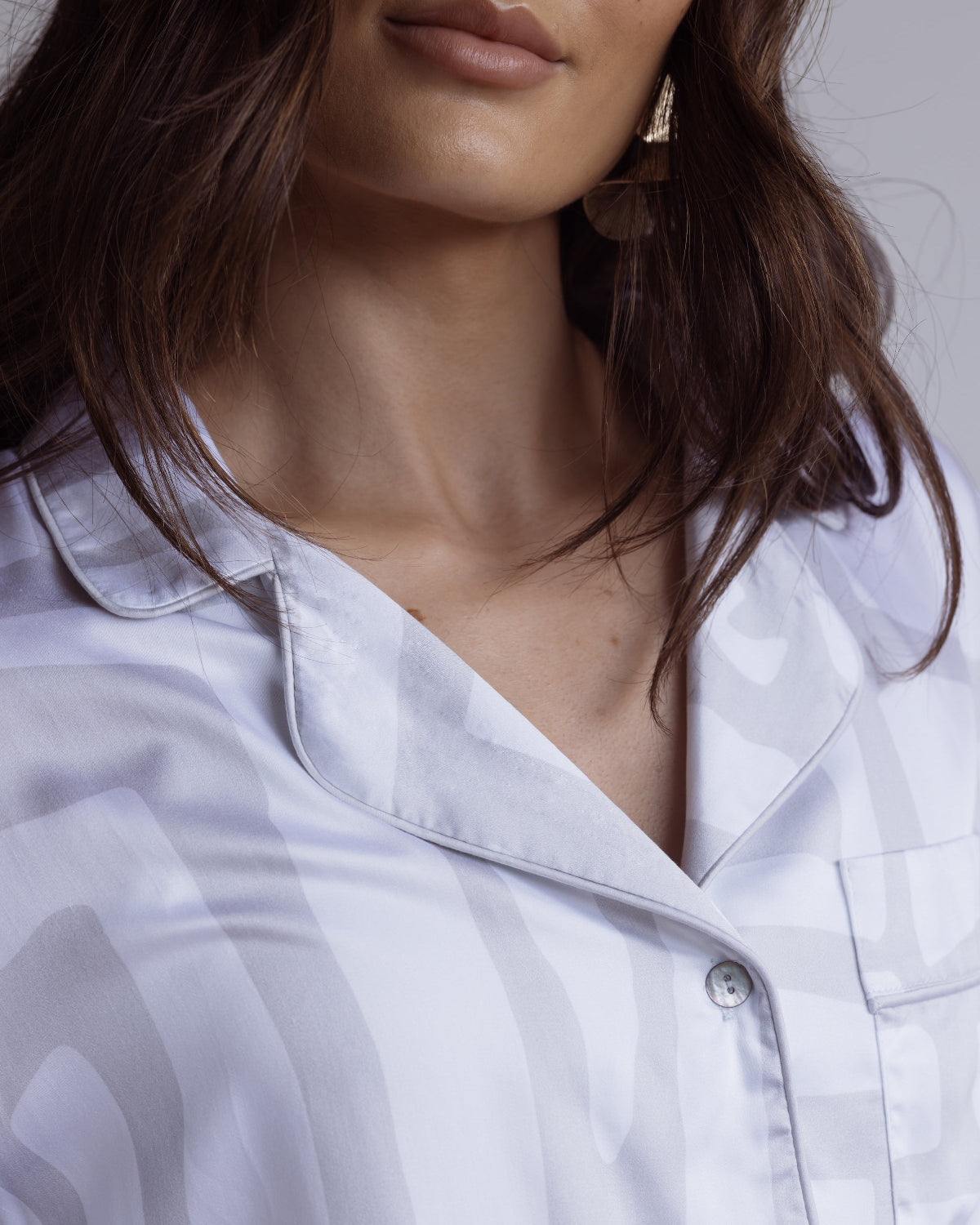 Close-up of a person wearing a white and grey bamboo satin shirt with a subtle pattern.