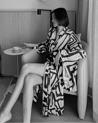 Woman sitting in wearing a black and cream kimono-style robe.