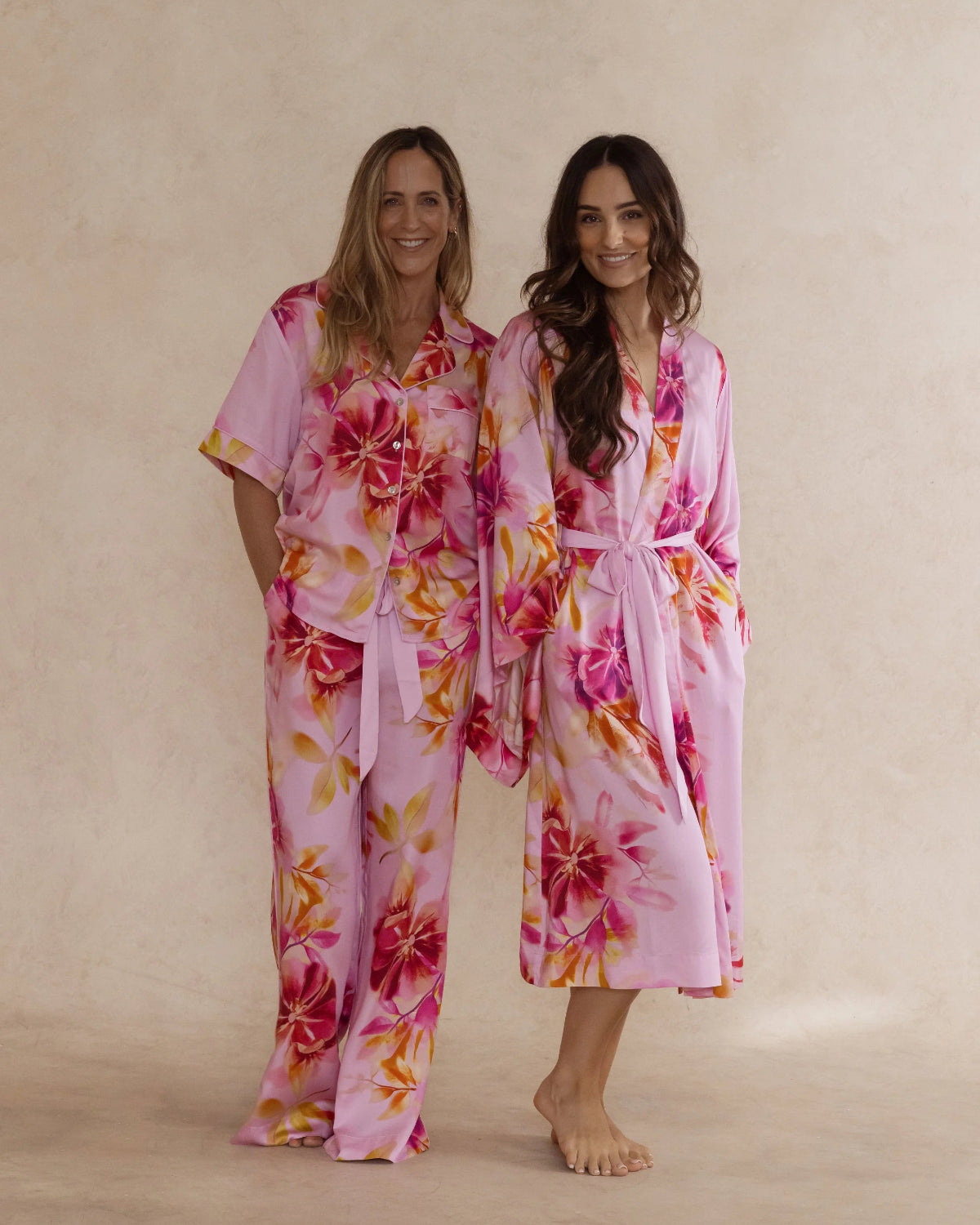 Two women in pink floral bamboo sleepwear. One in a kimono style robe, the other in a pyjama set with short sleeves and pants. These products are sold as a sleepwear bundle for extra savings.