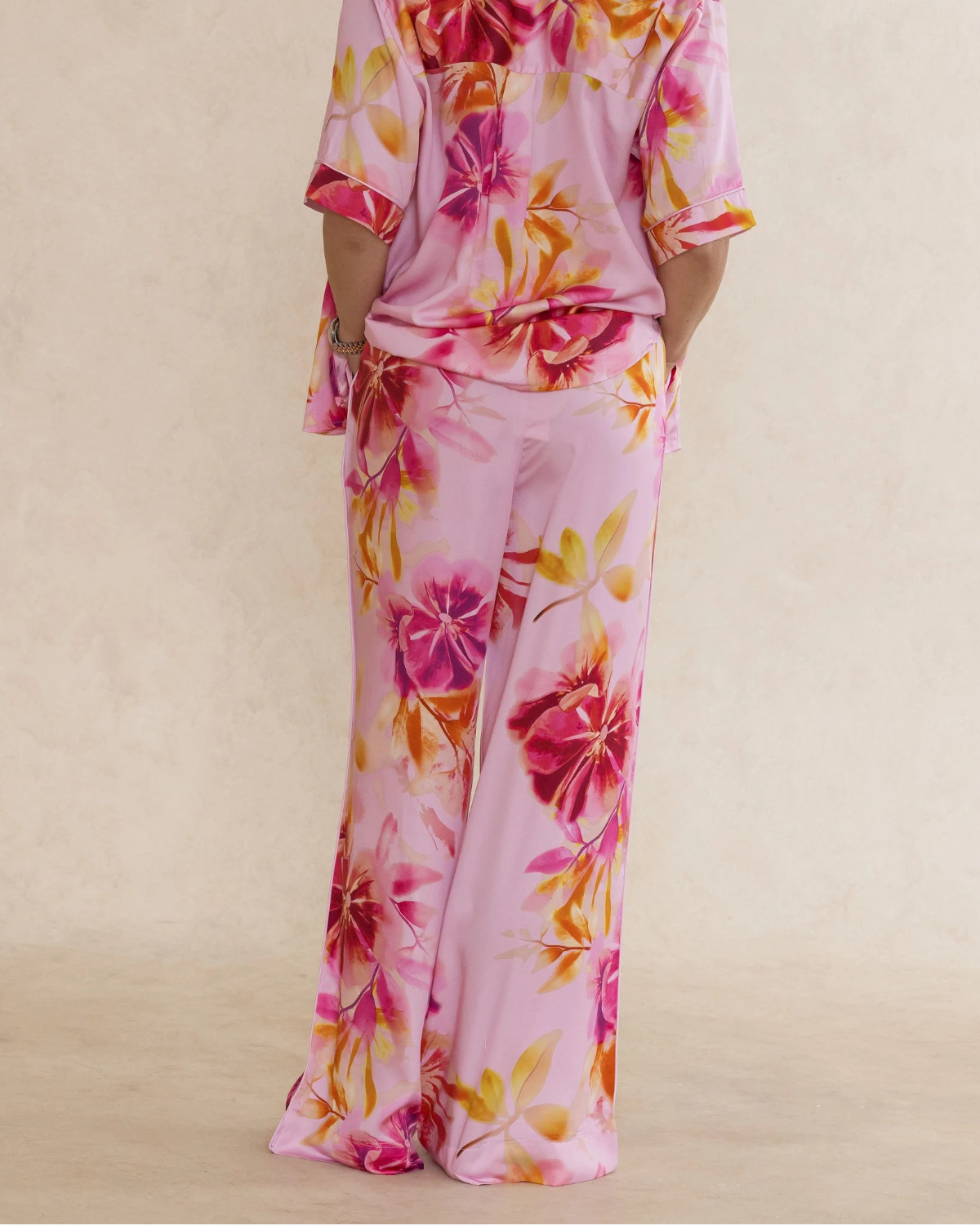 Woman wearing pink floral bamboo pants with pockets. Silky soft, elegant, breathable luxury sleepwear for women designed in Australia.