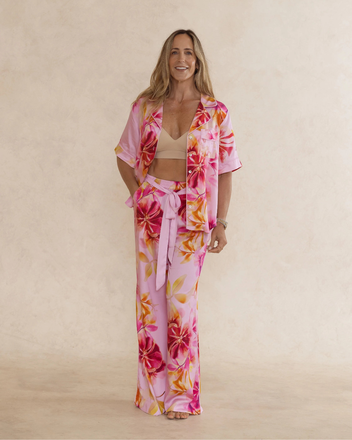 Woman wearing pink floral bamboo pyjama set with short sleeves and long pants. with pockets – soft, breathable women’s sleepwear designed in Australia