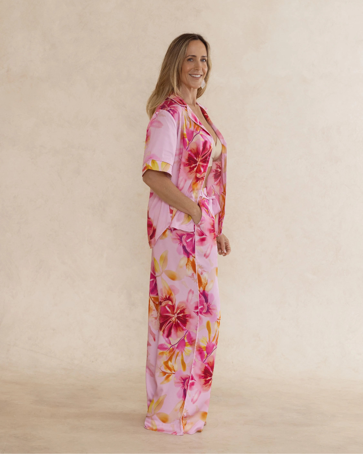Woman wearing bold pink floral bamboo pyjama set with short sleeves and long pants. with pockets – soft, breathable women’s sleepwear designed in Australia