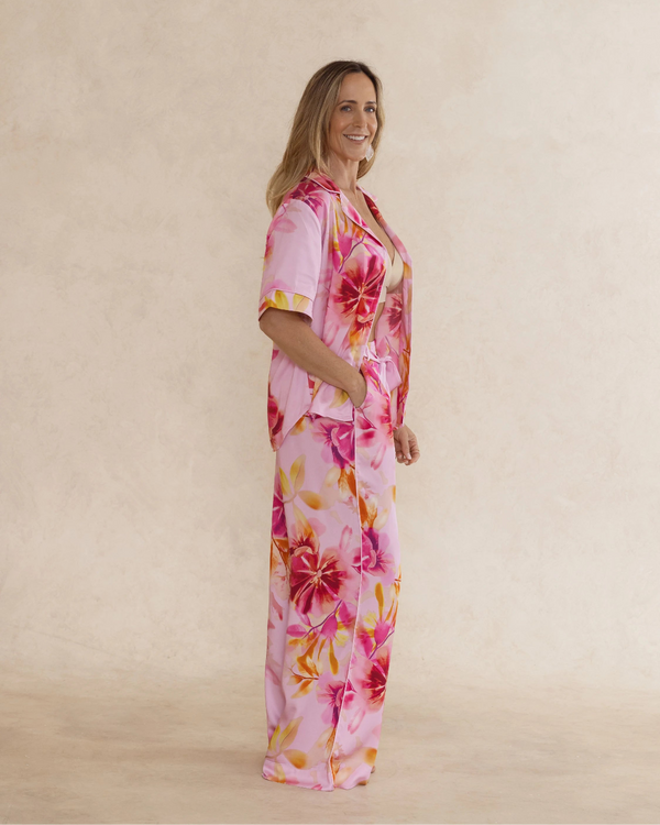 Woman wearing bold pink floral bamboo pyjama set with short sleeves and long pants. with pockets – soft, breathable women’s sleepwear designed in Australia