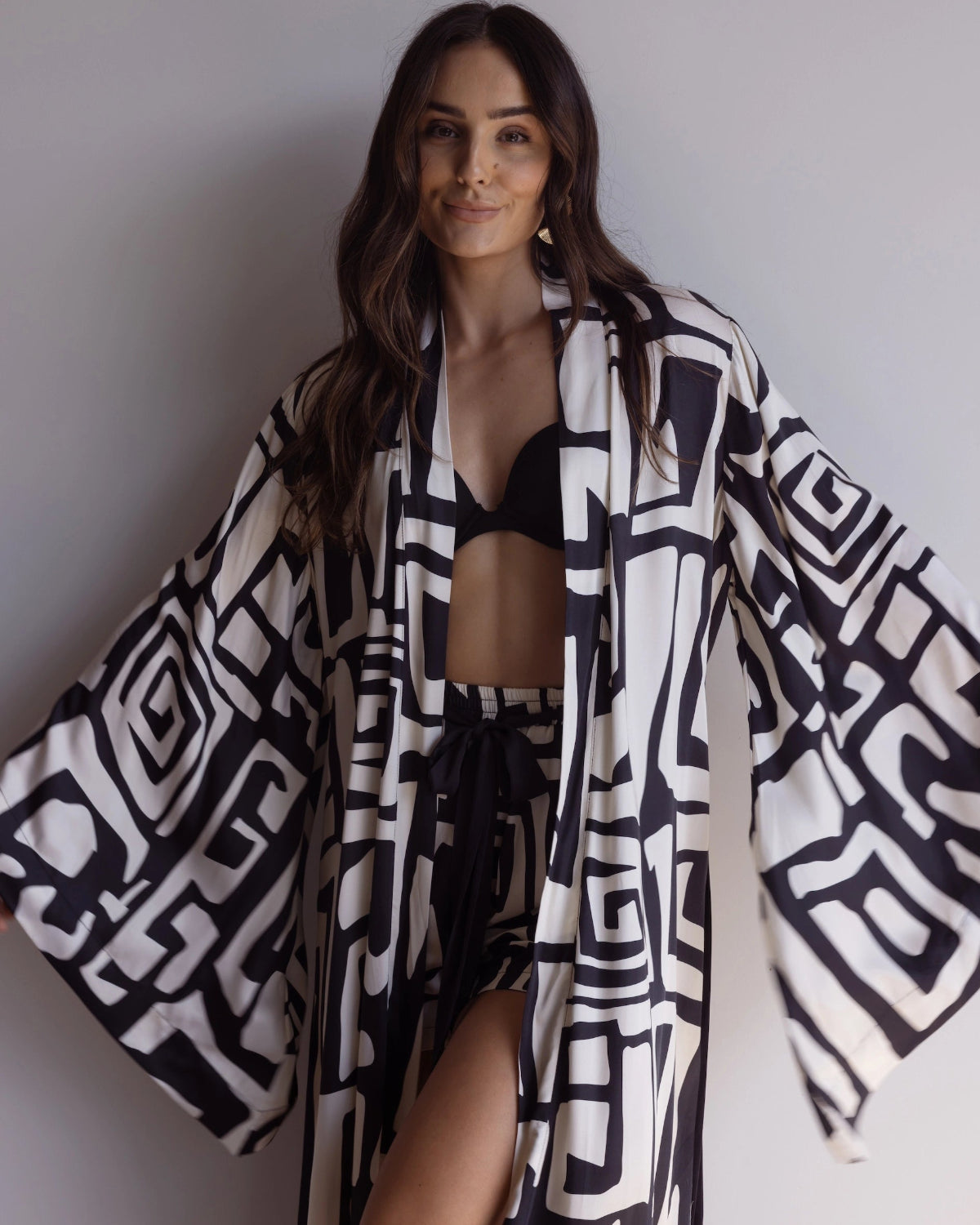 Woman wearing a black and white patterned kimono-styled robe, made from silky 100% bamboo satin