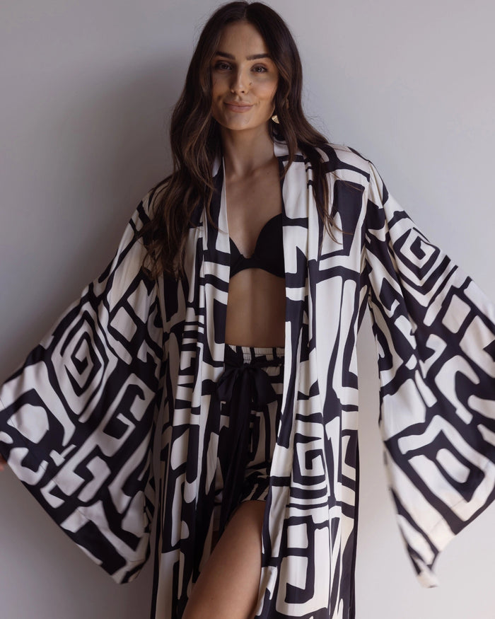 Woman wearing a black and white patterned kimono-styled robe, made from silky 100% bamboo satin