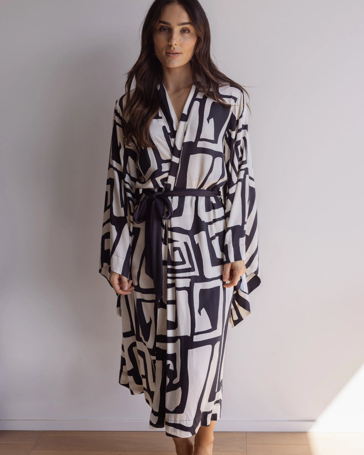 Woman wearing a black and cream robe. Made from silky-soft, breathable bamboo robe. With a tie waist for an adjustable fit, hidden pockets and wide sleeves. Perfect for lounging.