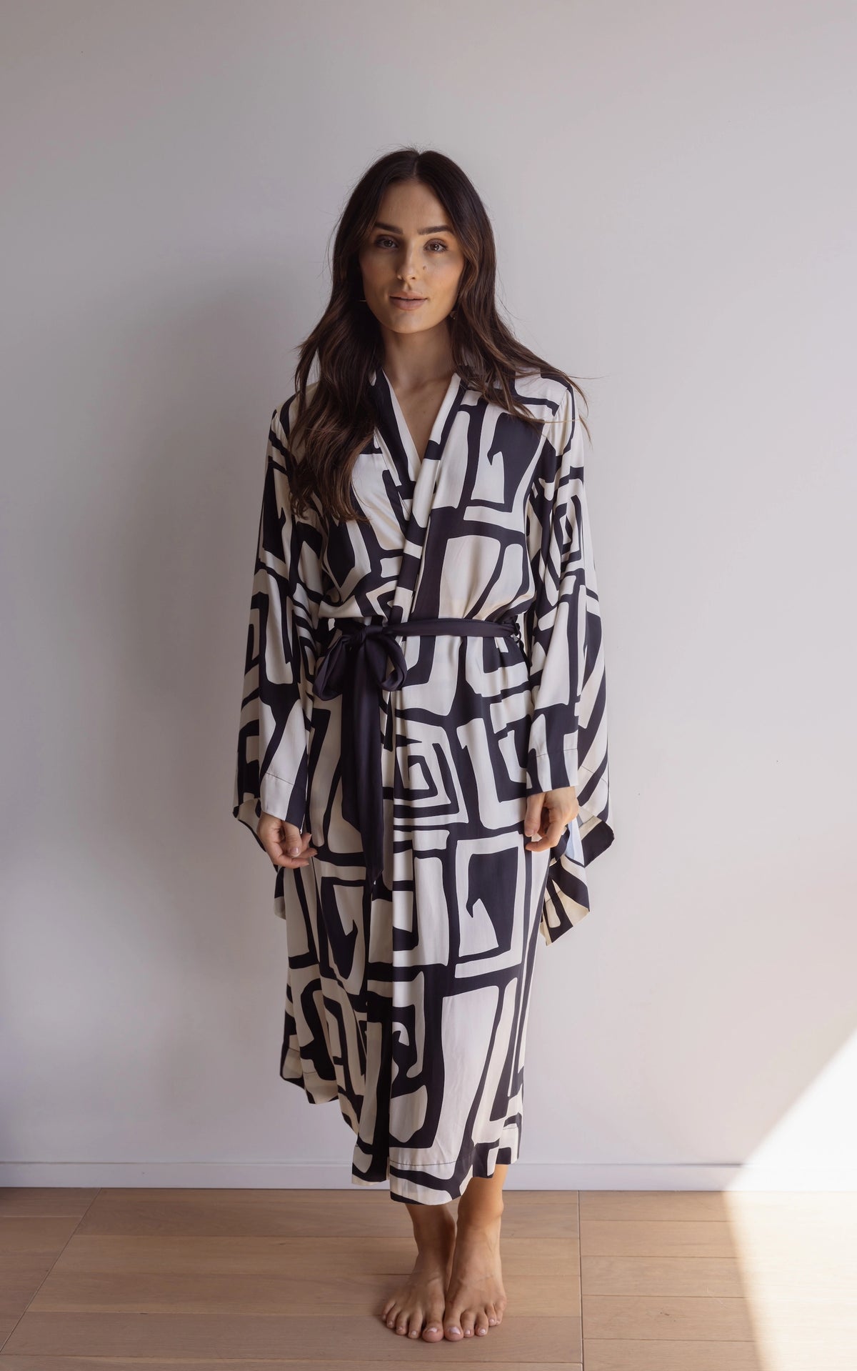 Woman wearing a black and cream robe. Made from silky-soft, breathable bamboo robe. With a tie waist for an adjustable fit, hidden pockets and wide sleeves. Perfect for lounging.