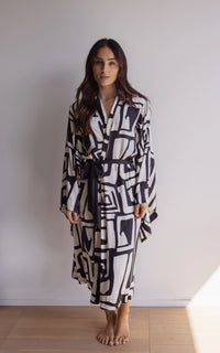Woman wearing a black and cream robe. Made from silky-soft, breathable bamboo robe. With a tie waist for an adjustable fit, hidden pockets and wide sleeves. Perfect for lounging.