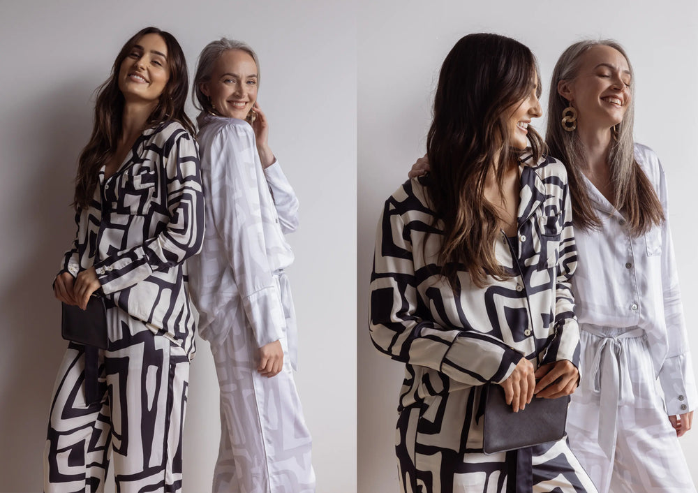 Two women wearing black and white patterned satin pyjamas with long sleeve and pants.