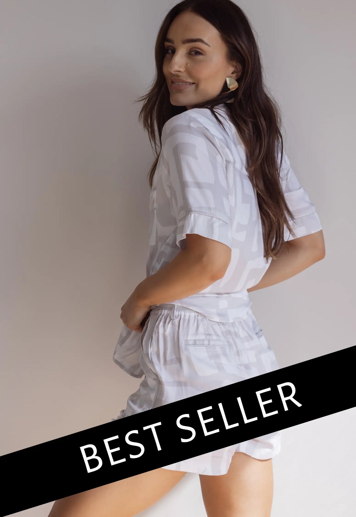 A female model wearing a short sleeve button-down bamboo pyjama top and matching PJ shorts with a graphic pattern, in a standing pose with a 'BEST SELLER' text overlay.