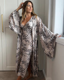 Woman wearing a muted leopard print slip dress and matching kimono style robe. Silky soft bamboo satin. Slip has a V neckline and kimono robe with wide dramatic sleeves.