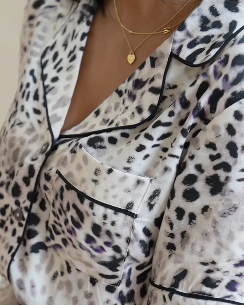 Close up of a pyjama top made from silky soft bamboo viscose satin in a muted leopard print. With dark piping, shell buttons and front pocket.