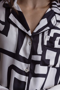 close up detail of a bamboo black and white pyjama top showing a collar with black piping, shell buttons and a pocket on the left side