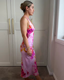 Woman wearing a pink floral slip dress with a low neckline and low back.