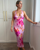 Woman wearing a pink floral slip dress made from bamboo satin, with low neckline.