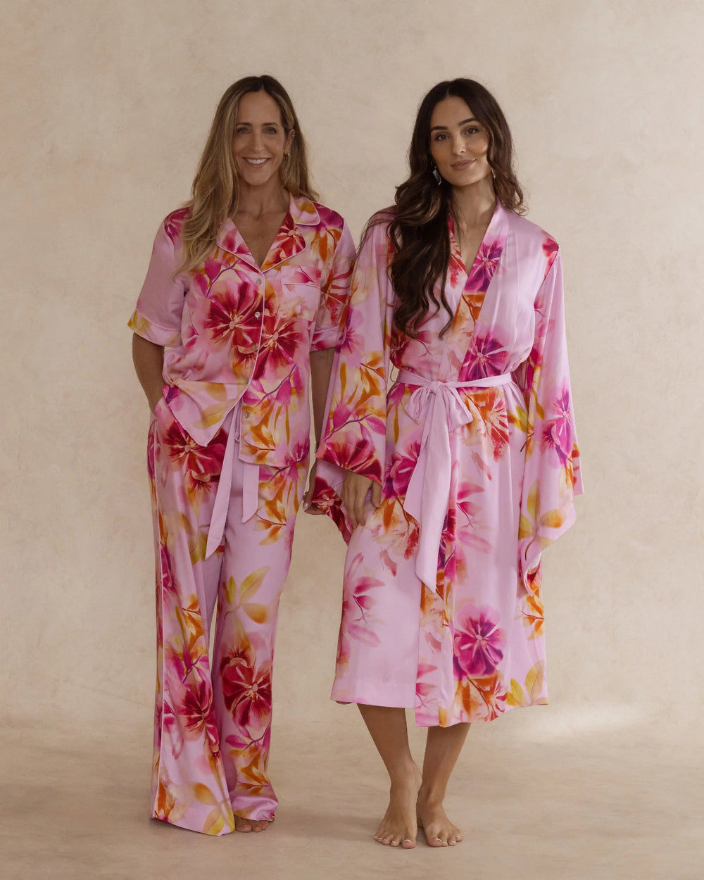 Two women in pink floral bamboo sleepwear. One in a kimono style robe, the other in a pyjama set with short sleeves and pants. These products are sold as a sleepwear bundle for extra savings.