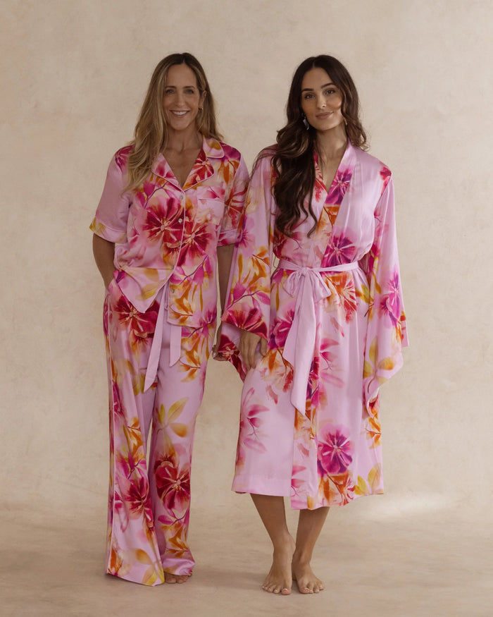 Two women in pink floral bamboo sleepwear. One in a kimono style robe, the other in a pyjama set with short sleeves and pants. These products are sold as a sleepwear bundle for extra savings.