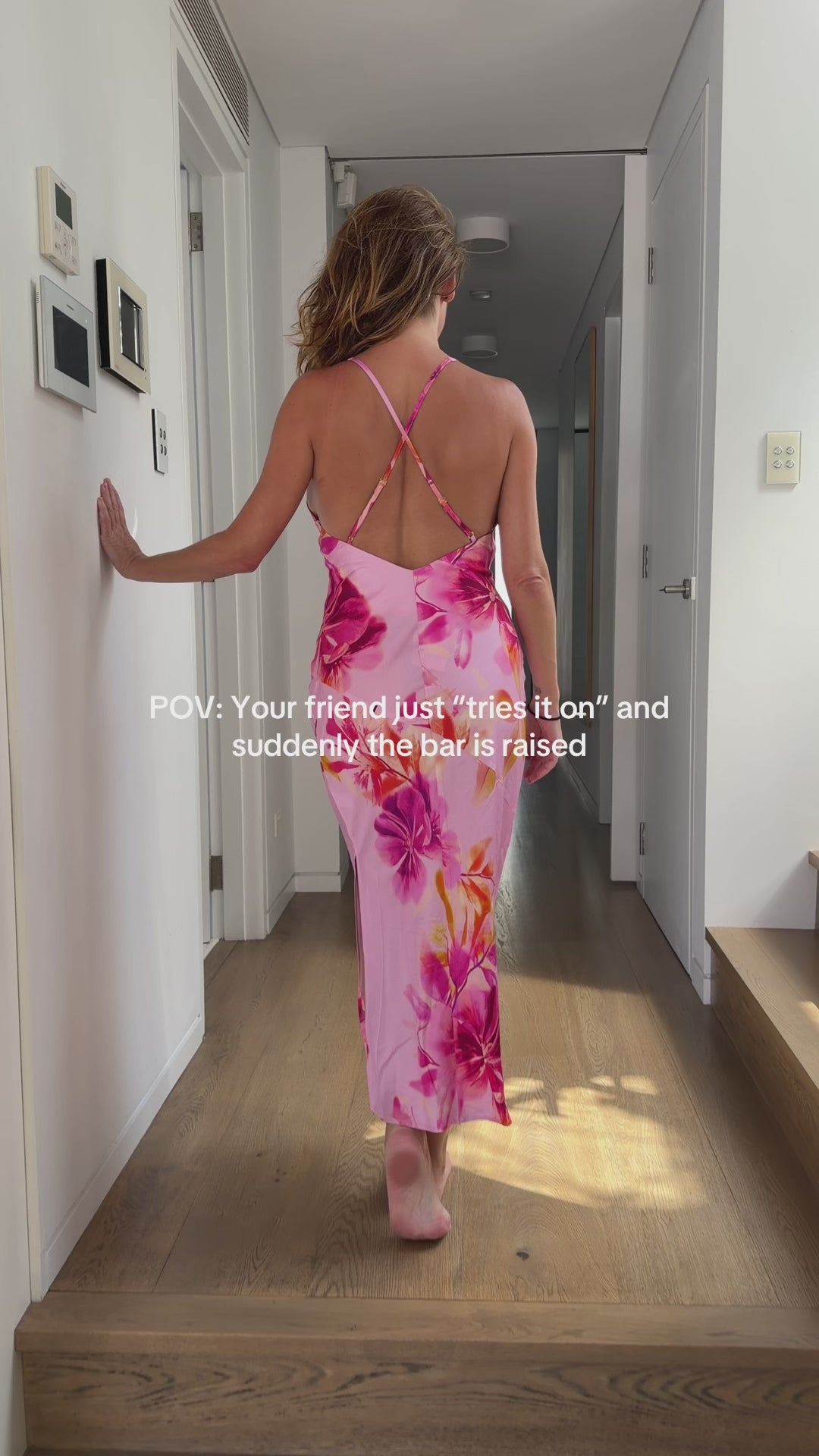 Woman wearing a pink floral slip dress with a low back and cross over spaghetti straps, she turns around to reveal a beautiful V neckline. Made from 100% bamboo satin.