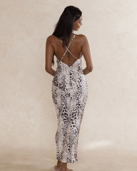 Woman wearing a silky soft leopard print dress with low back and cross over spaghetti straps.
