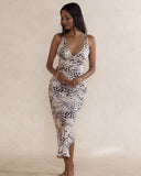 Woman wearing a silky soft leopard print slip dress with low neckline, side split and fitted style.